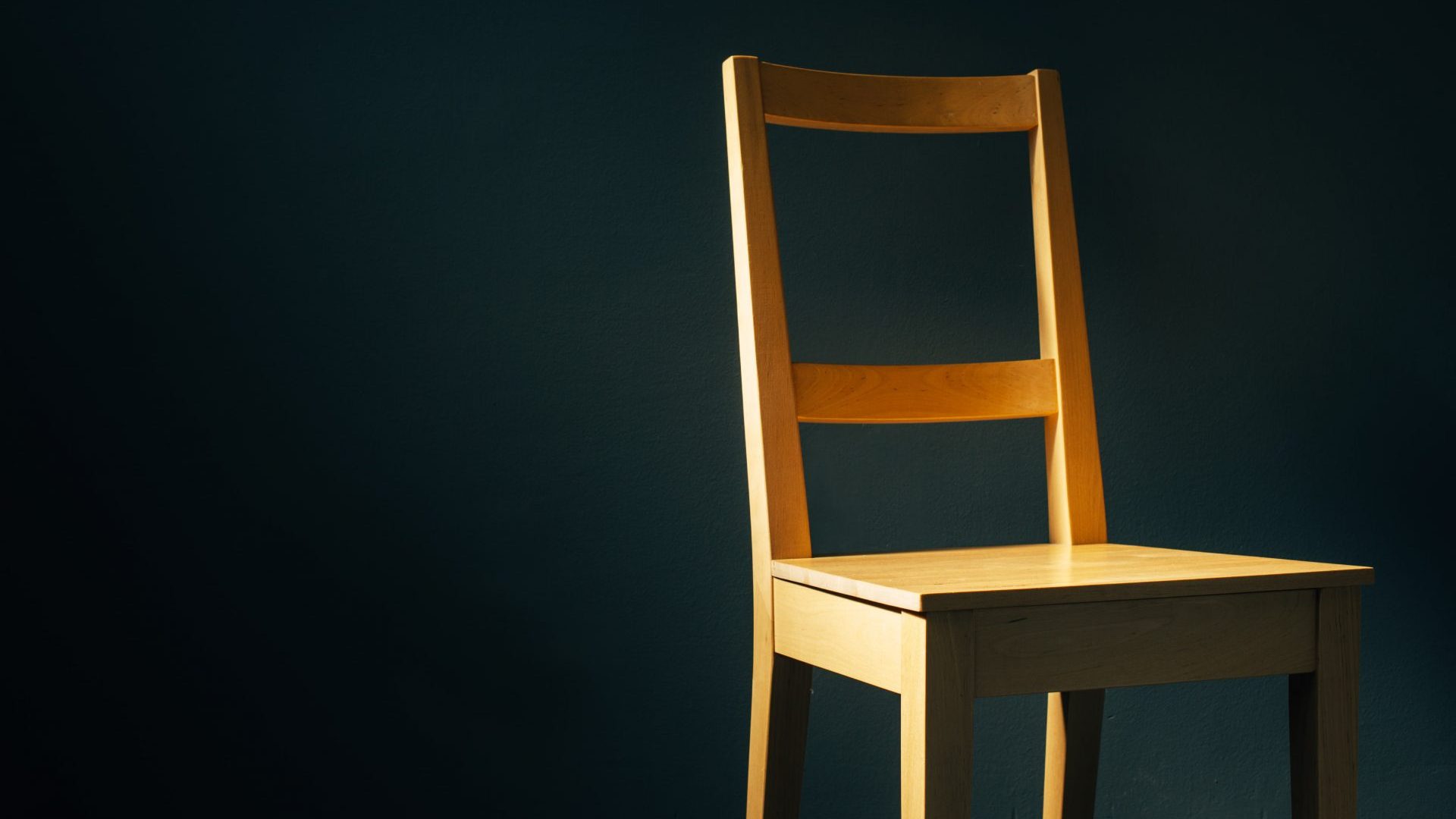 empty-wooden-chair-in-dark-room-PFJYSNE-min