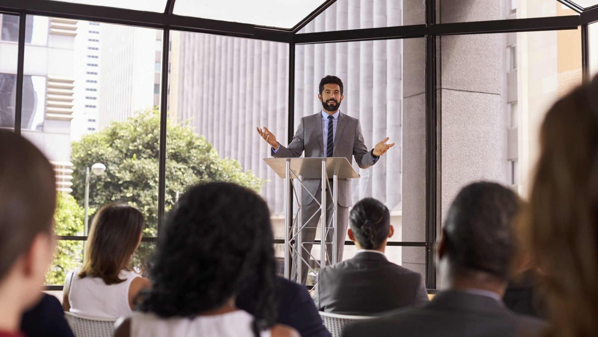 hispanic-man-gesturing-to-audience-at-business-PDUCYF9-min