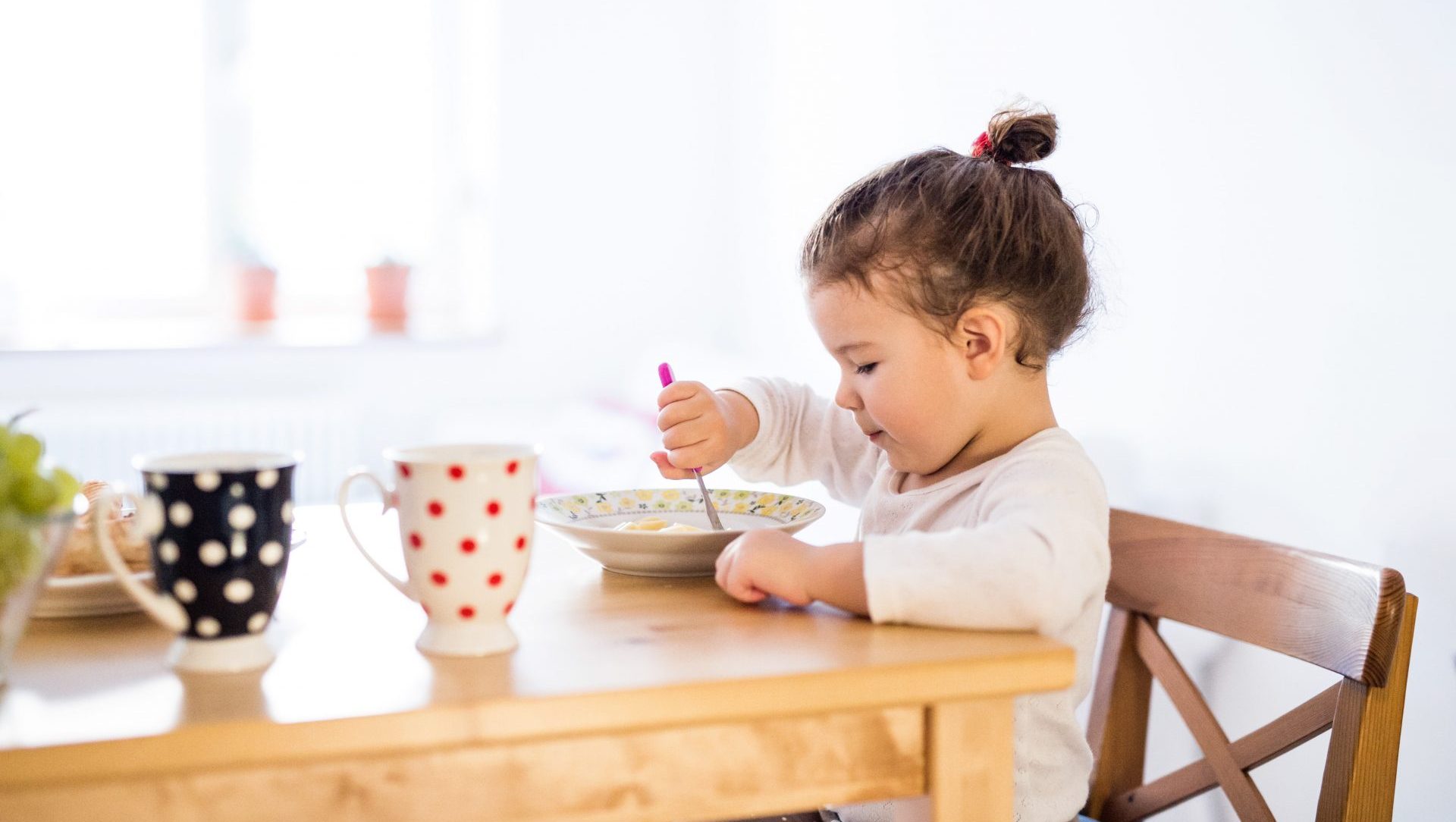 little-girl-sitting-at-the-table-eating-breakfast-PTQF2N8-min